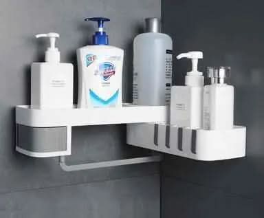 White corner bathroom shelf mounted on grey wall holding various soap and lotion bottles