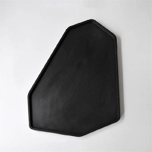 black irregular shaped cement tray with raised edges on white background