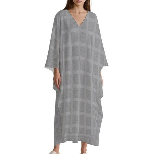 Woman wearing light gray V-neck kaftan dress with square pattern and wide sleeves