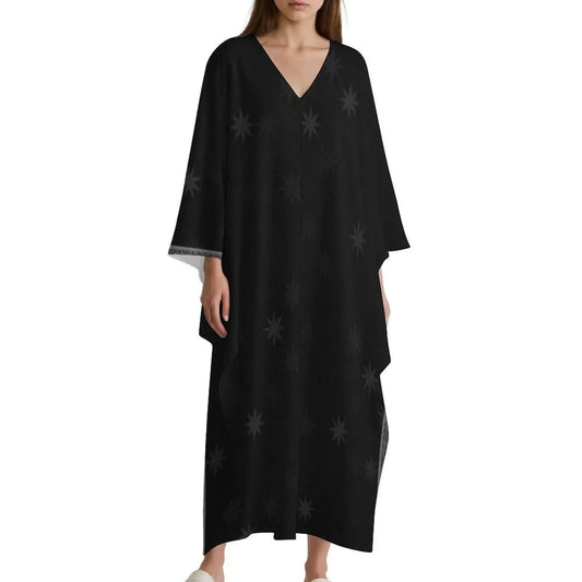 Woman wearing black V-neck kaftan dress with subtle star pattern and wide sleeves