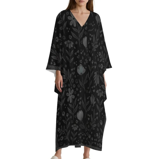 Woman wearing black V-neck kaftan dress with subtle gray floral pattern and wide sleeves