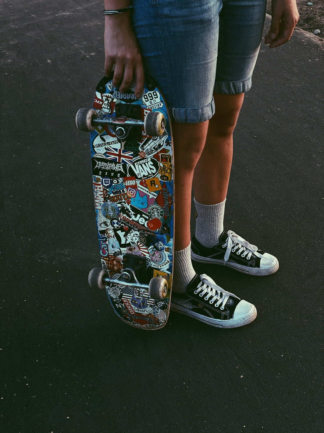 person in blue denim shorts and black and white nike sneakers riding skateboard
