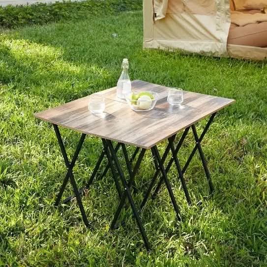 5-piece folding TV tray table set with wood grain tops and black metal legs on grass outdoors