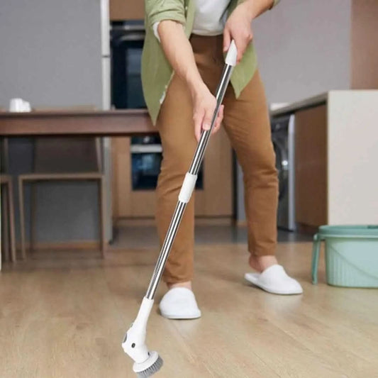 Person using a white cordless 8-in-1 cleaning brush with rotatable head on wooden floor in modern kitchen