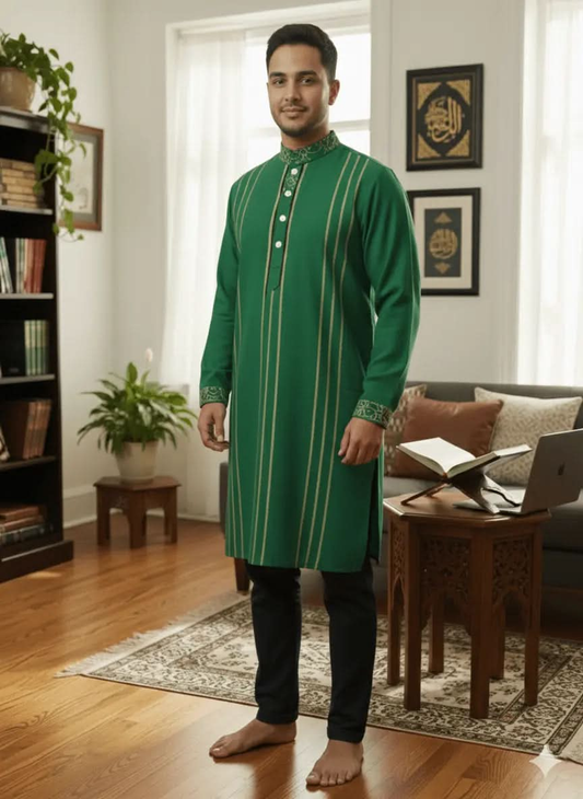 Man standing barefoot indoors wearing green traditional kurta with vertical stripes and embroidered collar and cuffs