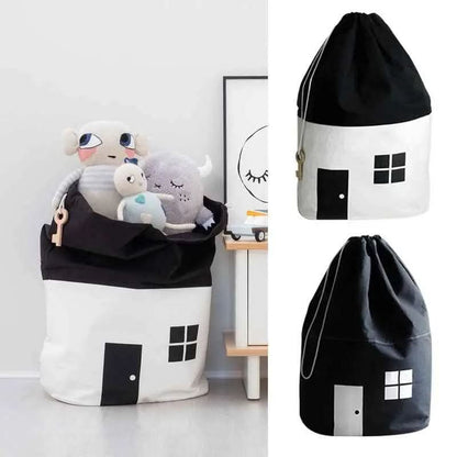 Black and white cotton canvas toy storage bags shaped like houses filled with plush toys in a child room setting
