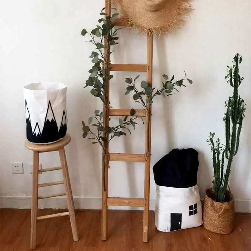 Decorative cotton canvas storage bags shaped like a house and mountain, wooden ladder with greenery, tall cactus in woven basket