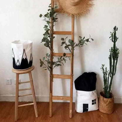 Decorative cotton canvas storage bags shaped like a house and mountain, wooden ladder with greenery, tall cactus in woven basket