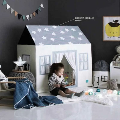 Child reading inside a cotton canvas playhouse with star roof, in a cozy kids room with toys and decor