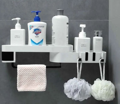white bathroom corner shelf holding lotion bottles, soap dispenser, pink washcloth, and two hanging bath sponges