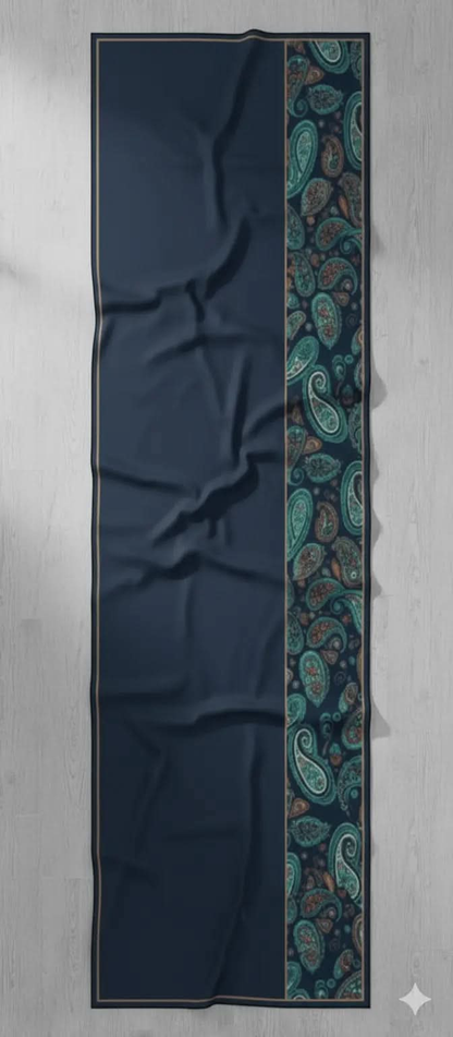 Blue bohemian scarf with paisley border design laid flat on light wooden floor