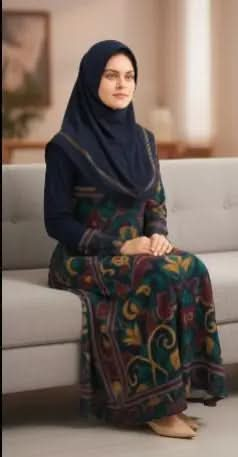 Woman wearing navy floral bohemian long sleeve dress and matching hijab sitting on beige sofa