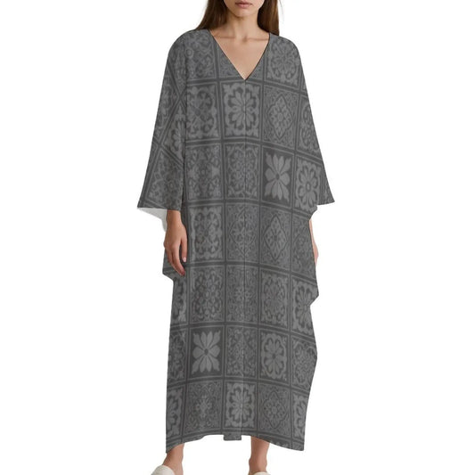 Woman wearing gray V-neck kaftan dress with floral tile pattern and wide sleeves on white background