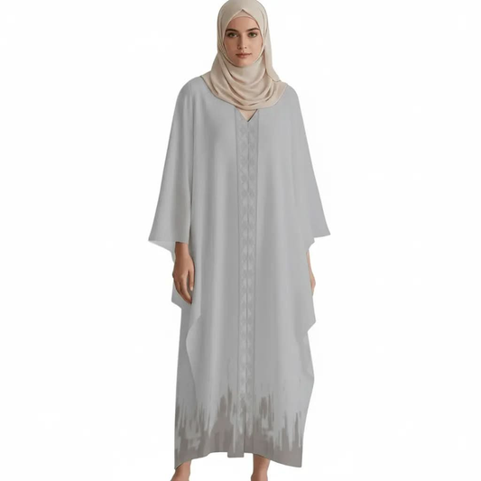 Woman wearing light grey V-neck kaftan dress with embroidery and beige hijab on white background