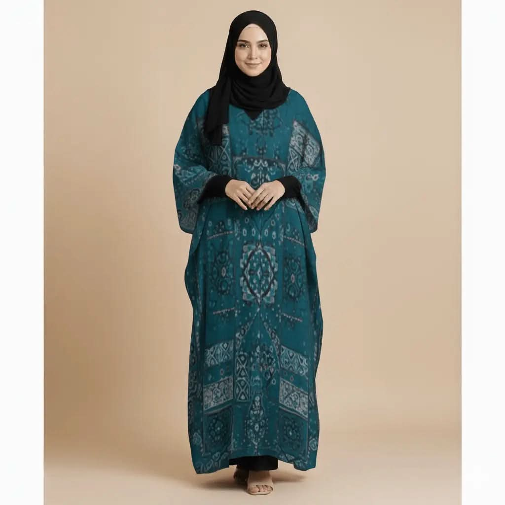 Woman wearing teal patterned V-neck kaftan dress with black hijab and sandals on beige background