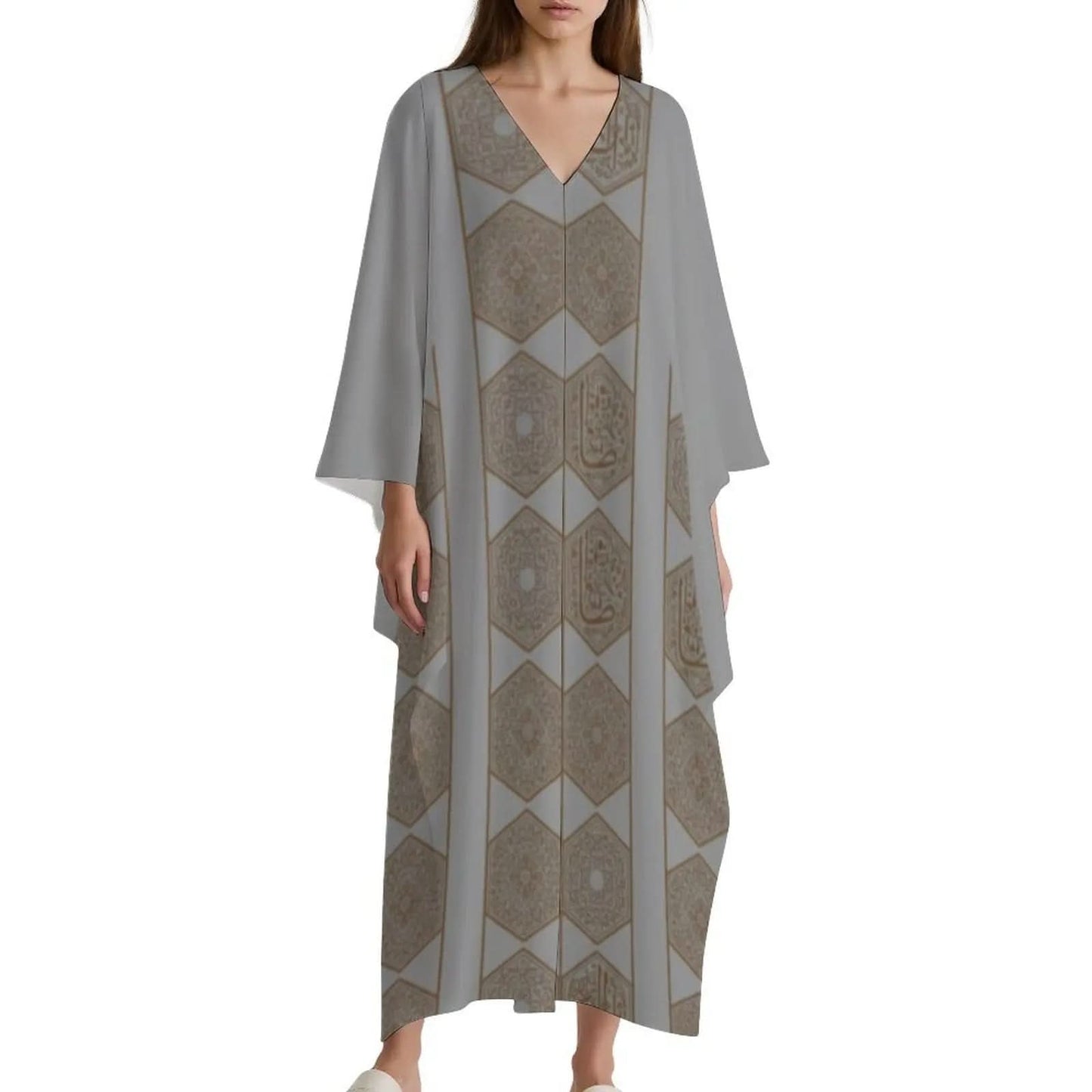 Woman wearing a long gray V-neck kaftan dress with hexagonal geometric patterns